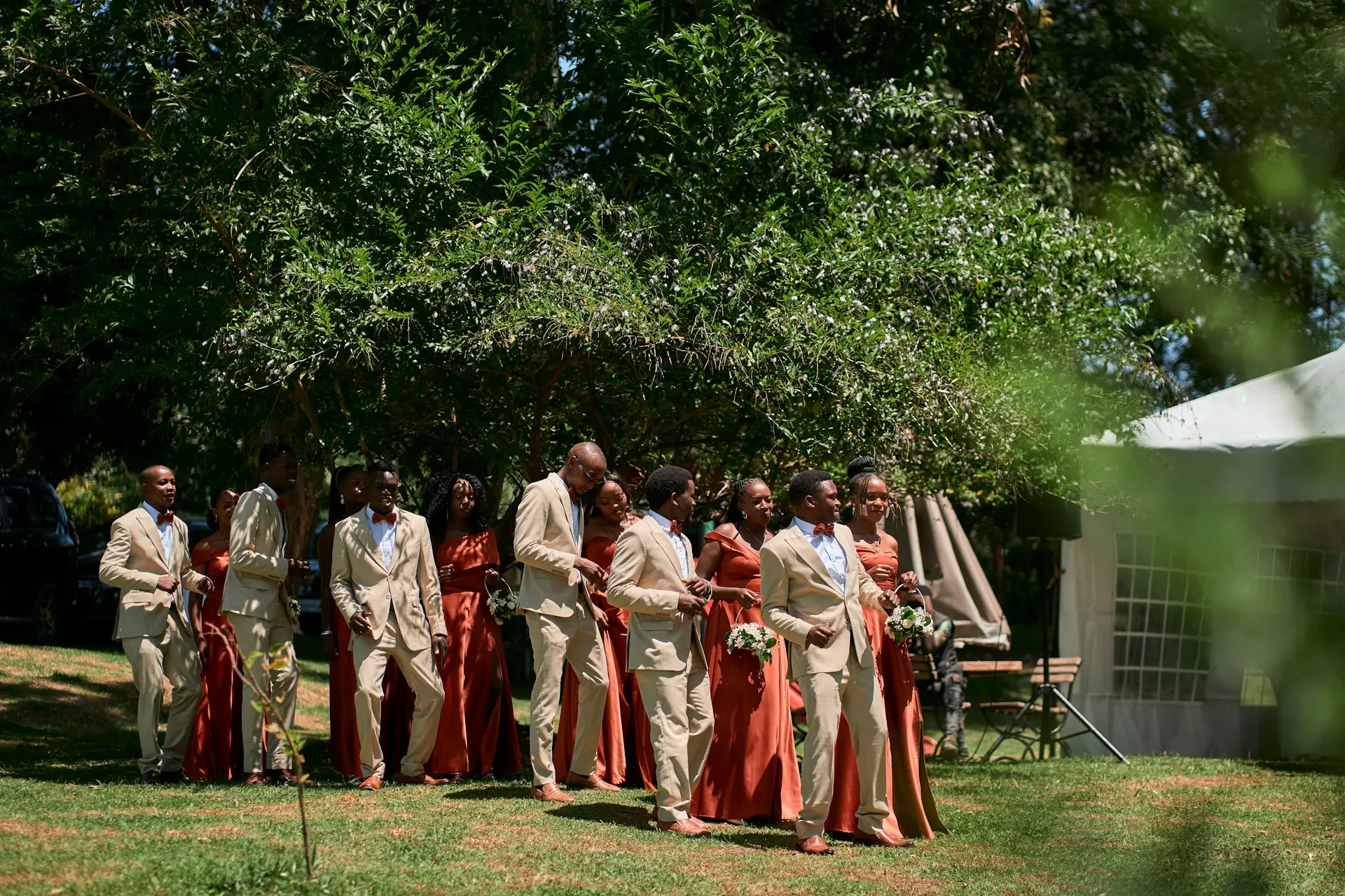 Padrinhos e madrinhas de casamento caminhando juntos em cerimônia ao ar livre.