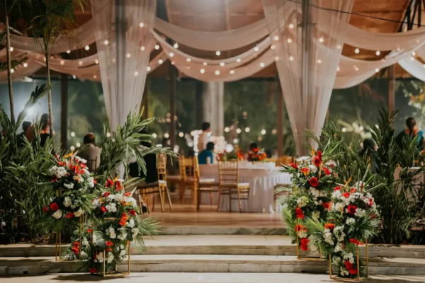 Imagem de um casamento decorado com flores tropicais e cortinas.