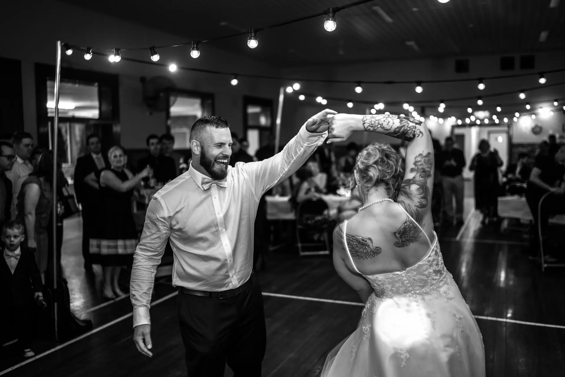 Noivos dançam juntos durante a festa de casamento, enquanto convidados acompanham a celebração ao redor.