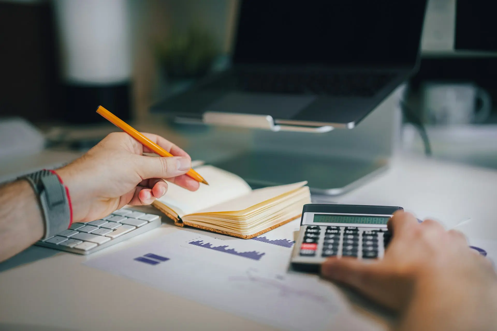 Planejamento financeiro para casamento: como organizar seu orçamento Imagem de uma pessoa fazendo planejamento financeiro, anotando valores em um caderno com o apoio de uma calculadora.