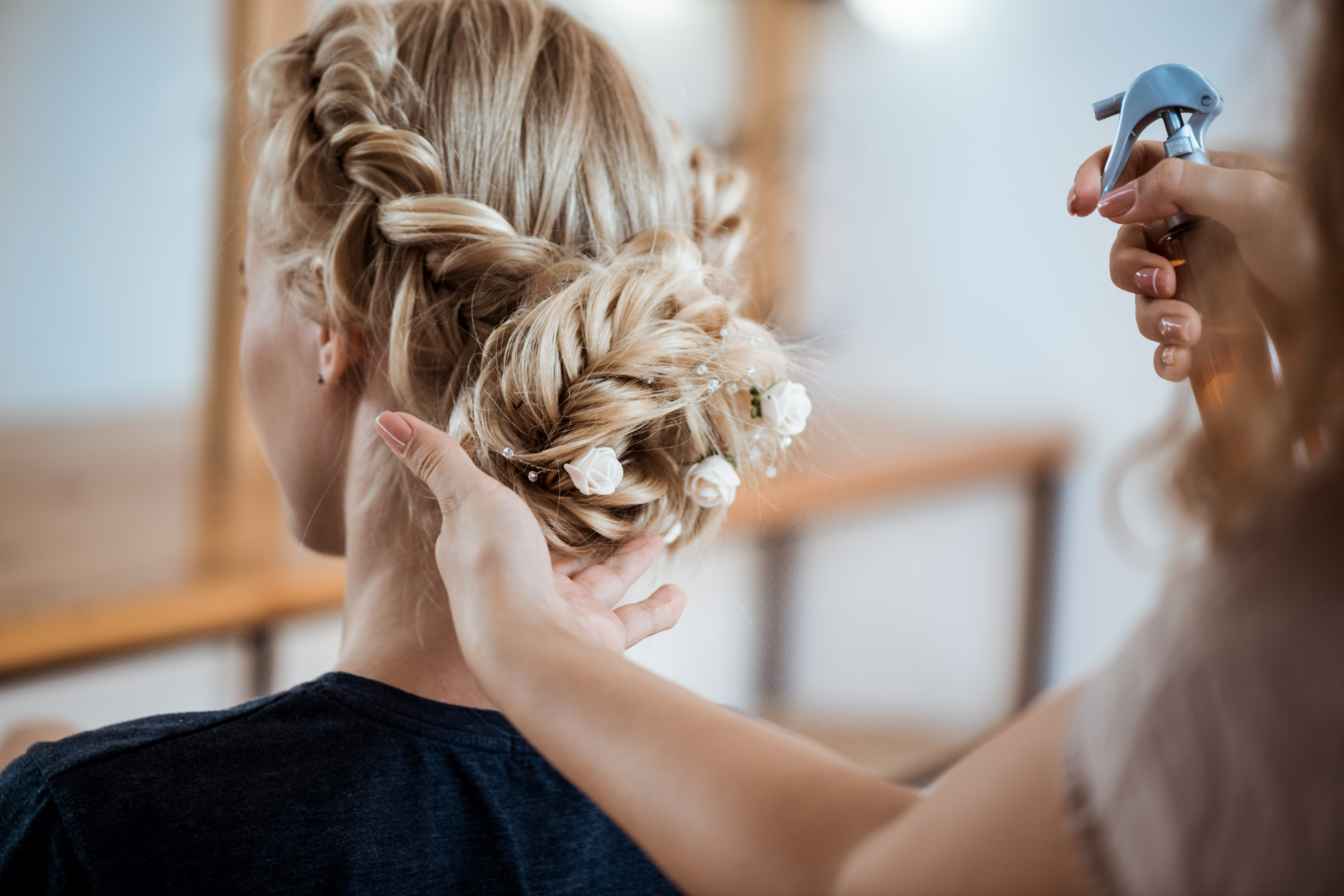 Penteados para madrinhas de casamento: opções para todos os tipos de cabelo e rosto Imagem mostra uma mulher em um salão de beleza, fazendo um penteado com a ajuda de um profissional, que trabalha cuidadosamente em seu cabelo