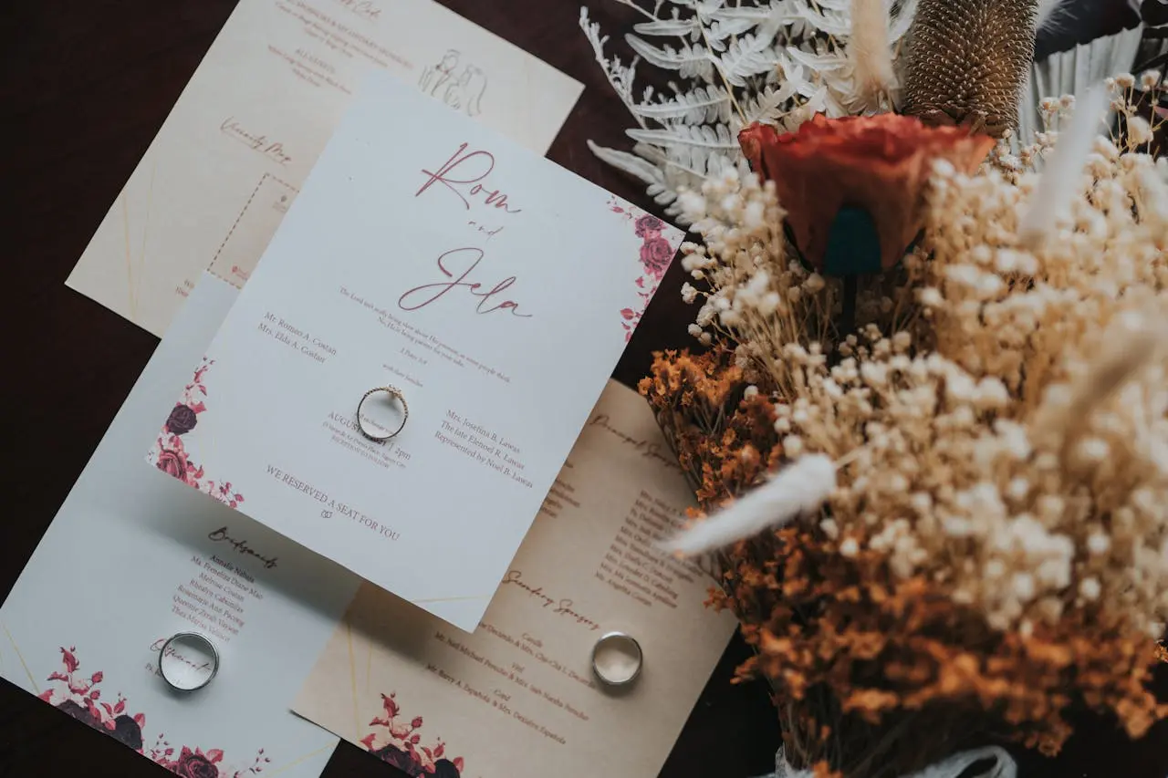 Imagem de convites de casamento com um anel sobre eles e, ao lado, flores decorativas