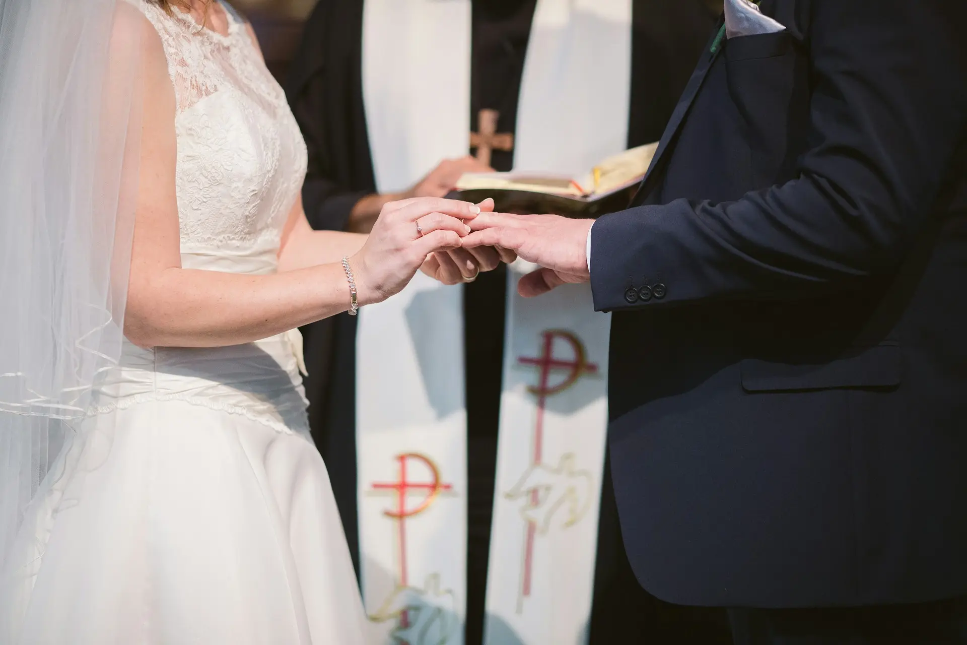 Noiva colocando aliança no dedo do noivo durante cerimônia de casamento religioso.