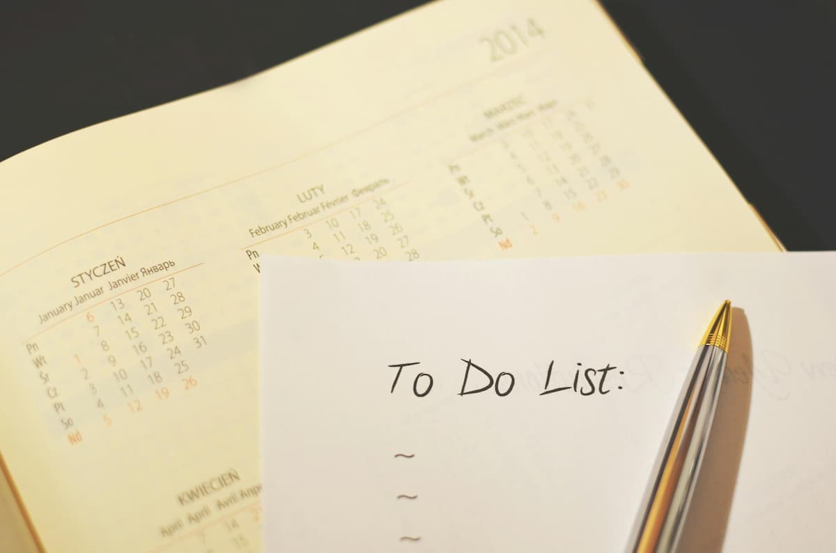 Folha com a inscrição “To Do List” ao lado de um calendário e uma caneta, representando uma lista de preparativos para casamento.