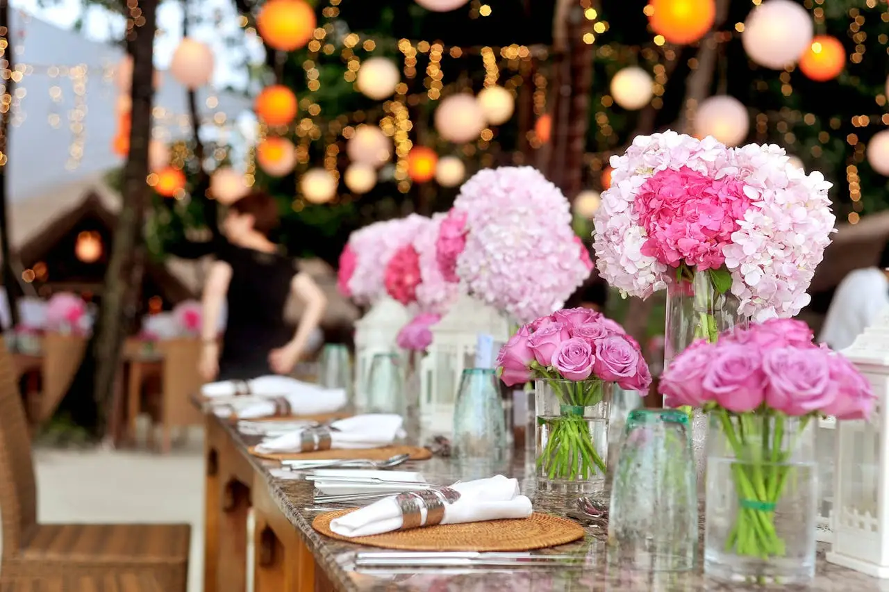 Imagem de uma mesa com decoração de casamento, com pratos organizados e flores dispostas sobre a mesa.