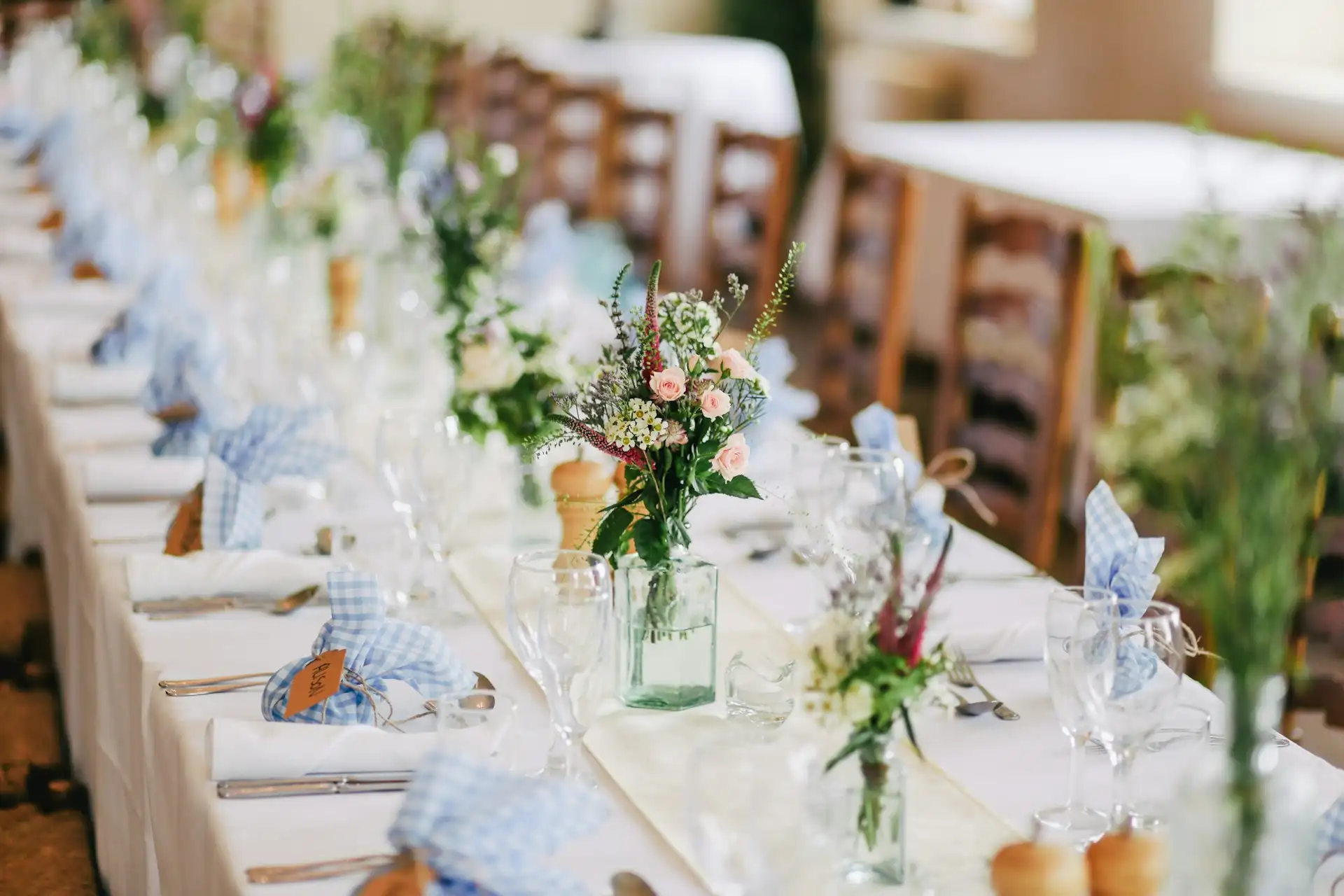 Imagem de uma mesa com decoração de casamento, com talheres e vaso de flores.