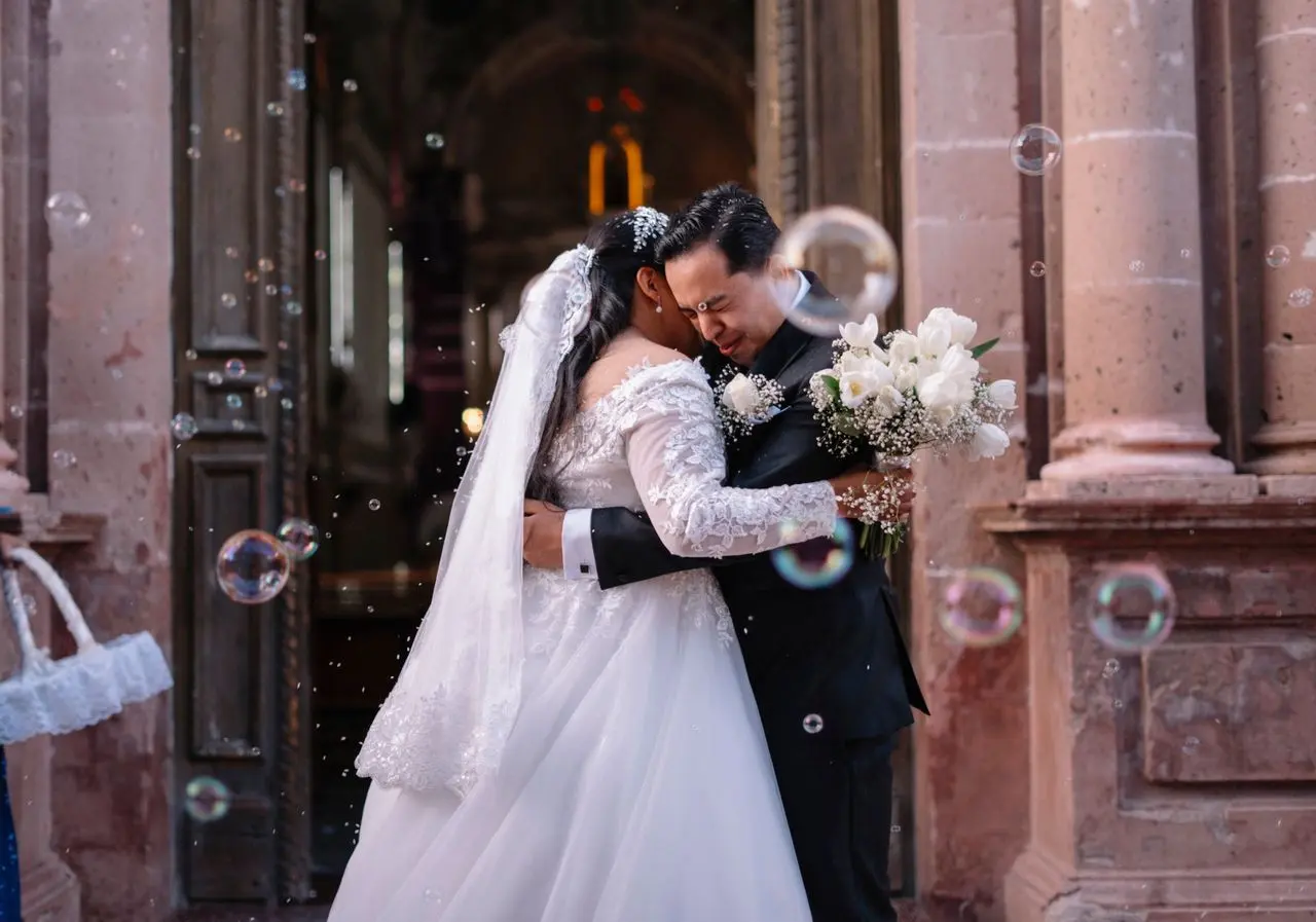 Texto para site de casamento: ideias para contar a história do casal Noivos se abraçam na saída da cerimônia de casamento, cercados por bolhas de sabão.