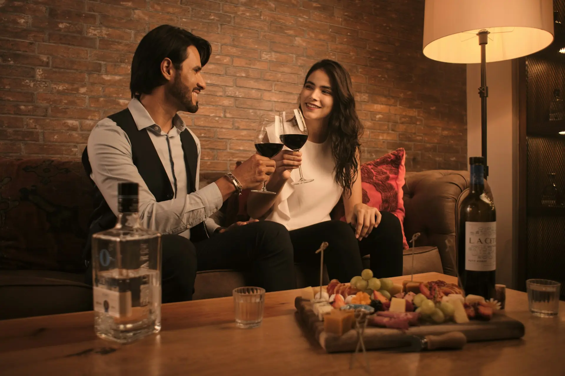 Casal sentado no sofá segurando taças de vinho.
