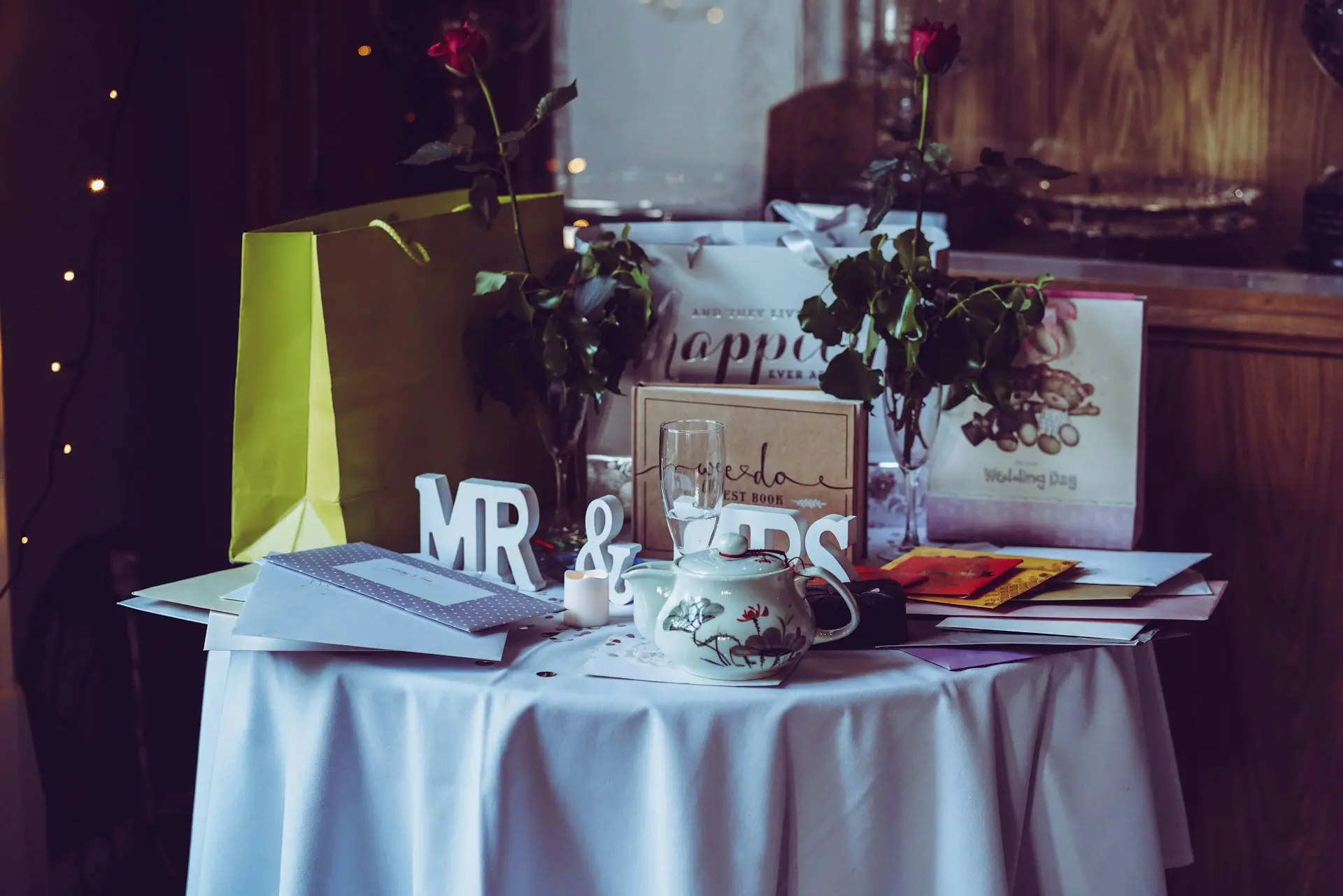 Mesa de casamento decorada com cartões, presentes, flores e objetos com as letras “MR & MRS”.