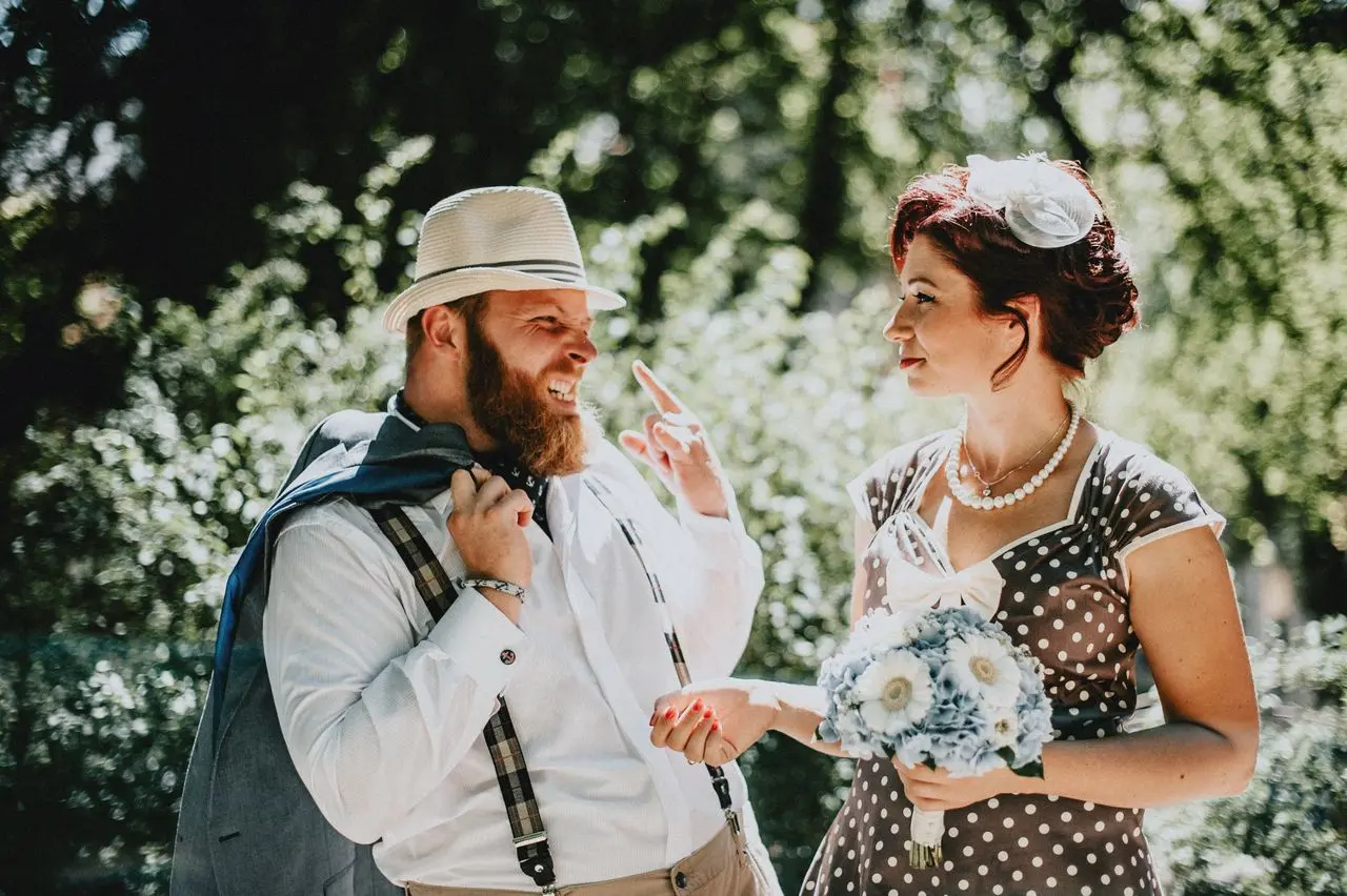 Casal de noivos em casamento ao ar livre, com a noiva segurando um buquê de flores.
