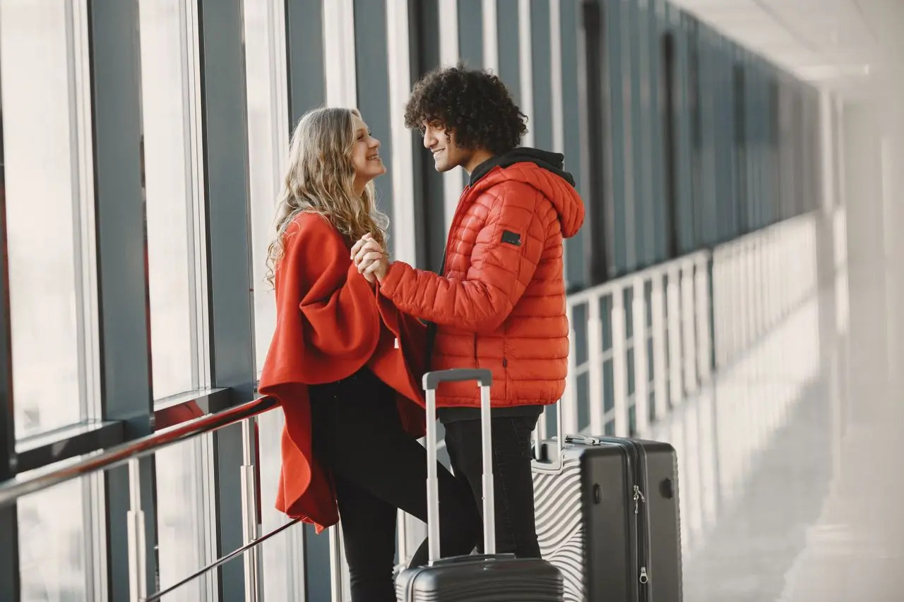 Casal com malas em área de embarque de aeroporto antes de uma viagem.