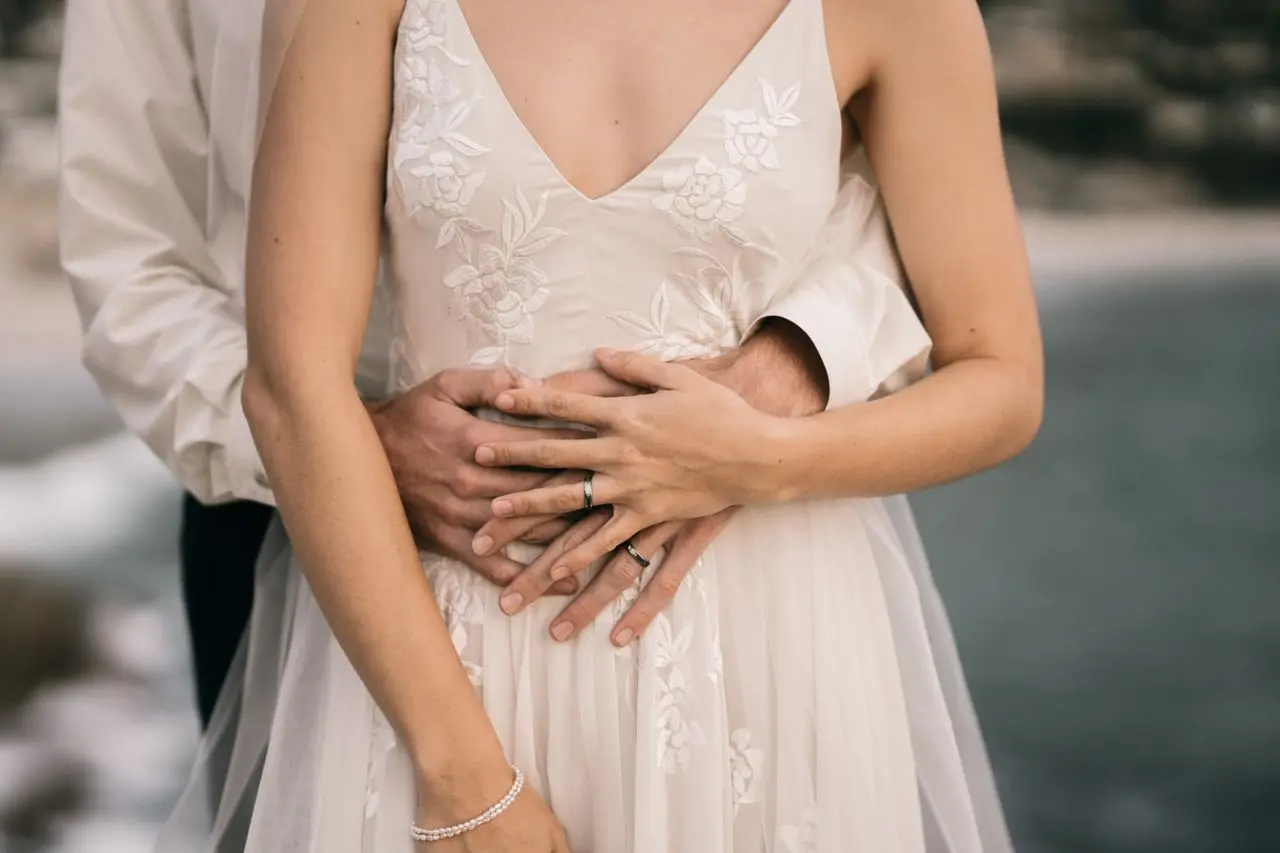 Detalhe de vestido de noiva em tule branco, com saia leve e transparente, corpete com bordados florais e decote em V.